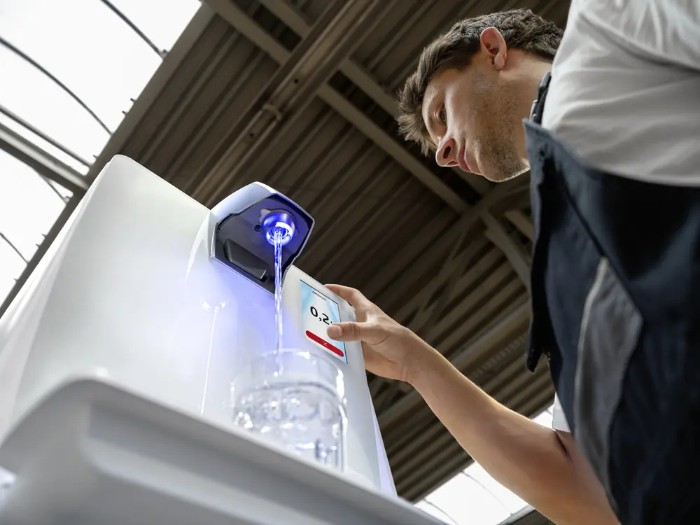 Mitarbeiter neben einem weißen Kärcher Wasserspender im Pausenbereich einer Werkstatt