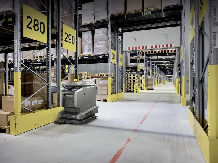 KIRA Scheuersaugroboter in einem Regalgang eines Logistiklagers