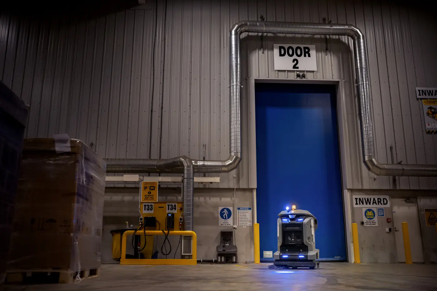 KIRA Scheuersaugroboter vor einem Rolltor in einer Logistikhalle