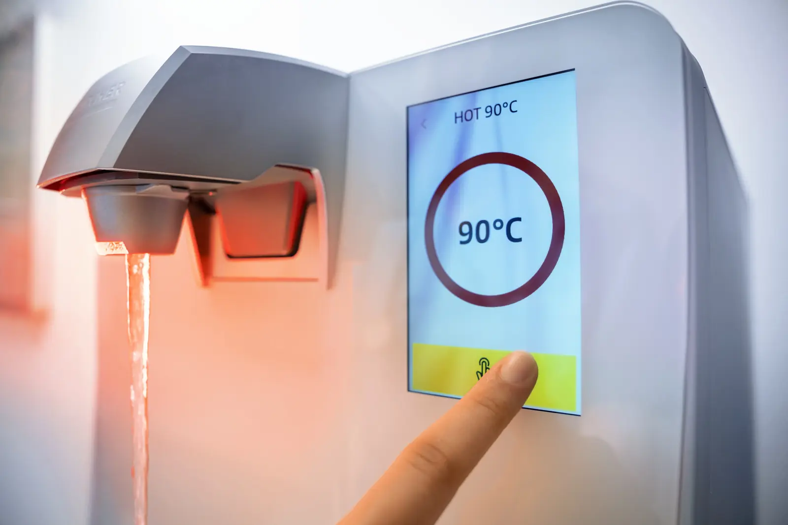 Touchdisplay des Wasserspenders zeigt 90 °C, darunter läuft heißes Wasser
